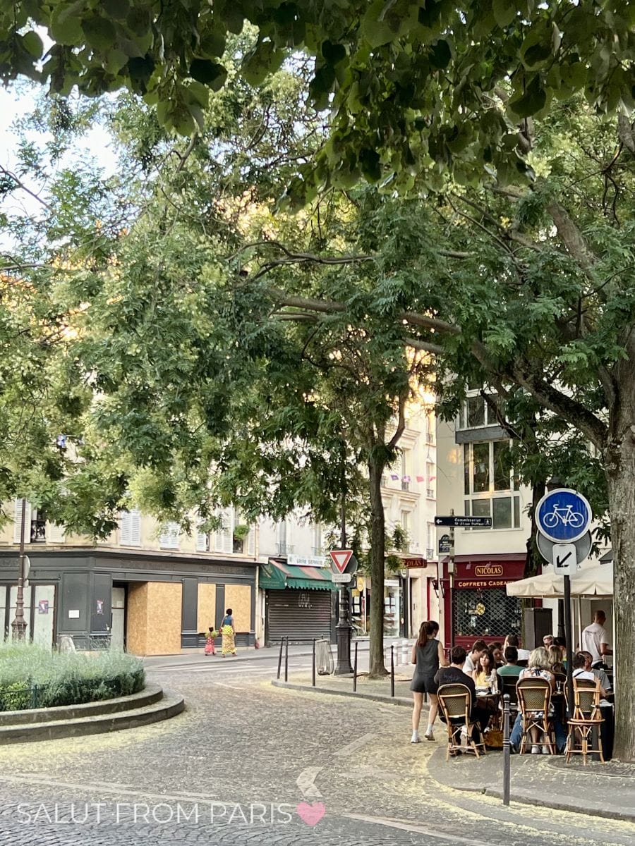 Locals enjoying drinks on a shaded terrace in a quiet Paris neighborhood during August