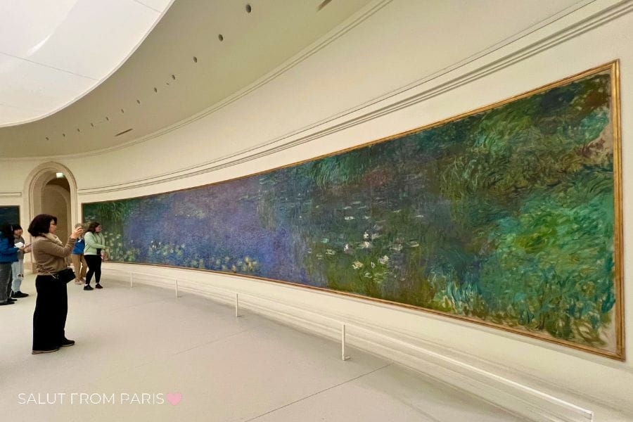 Oval room in Musรฉe de l'Orangerie with waterlilies painting and women taking picutres