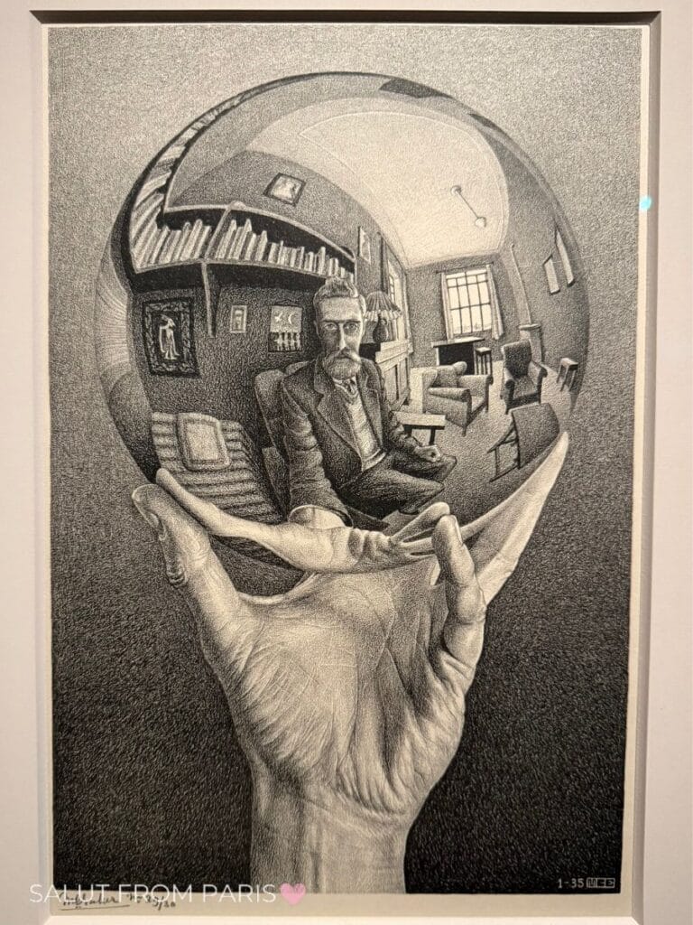 Black-and-white Escher artwork depicting a man seated in a room, reflected inside a round mirror held in a hand