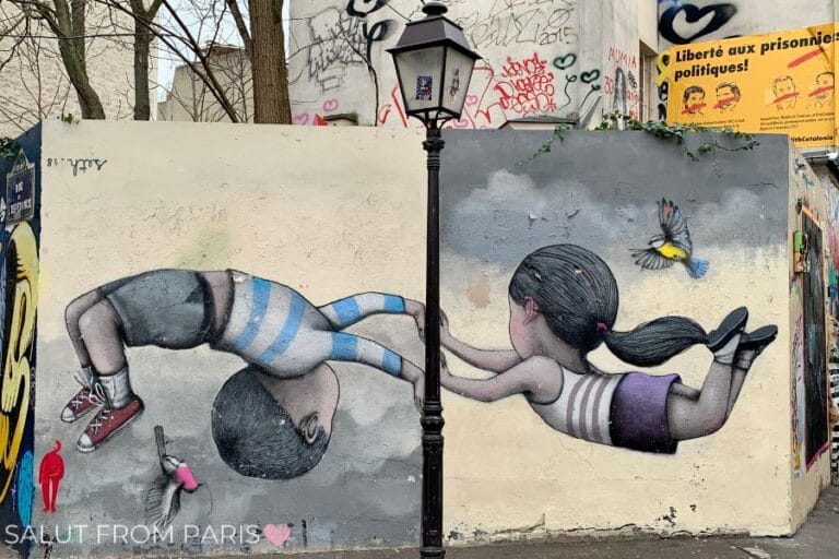 This image showcases a vibrant street art mural on a wall in Paris. The artwork depicts two children floating in the air, with one holding onto a street lamp for balance, while a bird flies nearby. The scene is playful and whimsical, blending urban elements with imagination.